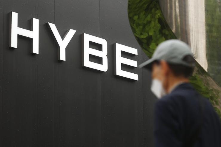 A man is seen walking past the headquarters of HYBE. 

Image Source: The Korea Times 